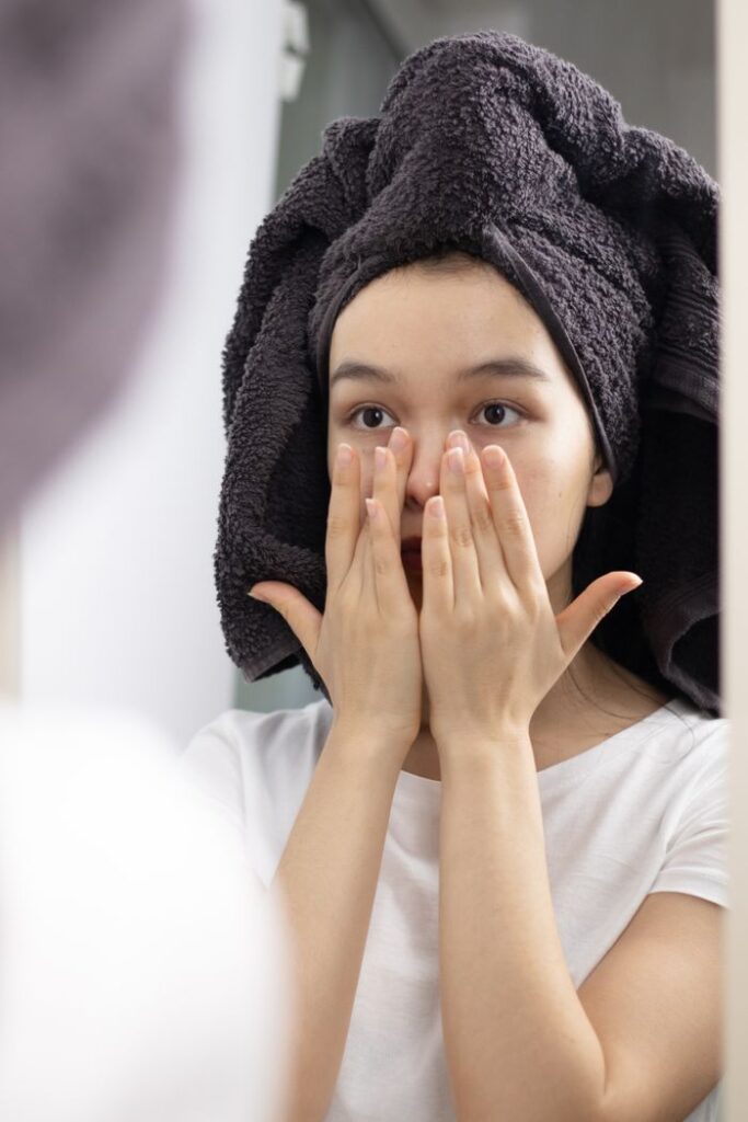 Close-up of a woman patting her face in the mirror, promoting skincare and relaxation at home.
